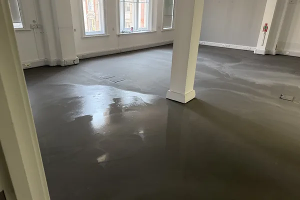 Latex screed poured level across a nursery floor before the vinyl went down