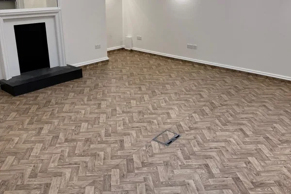 Herringbone flooring laid through a period room with a fireplace and shutters