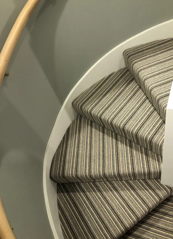 Striped runner turning a spiral staircase, pattern held straight through the winders