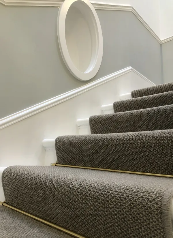 Stair runner held by brass rods on a painted staircase