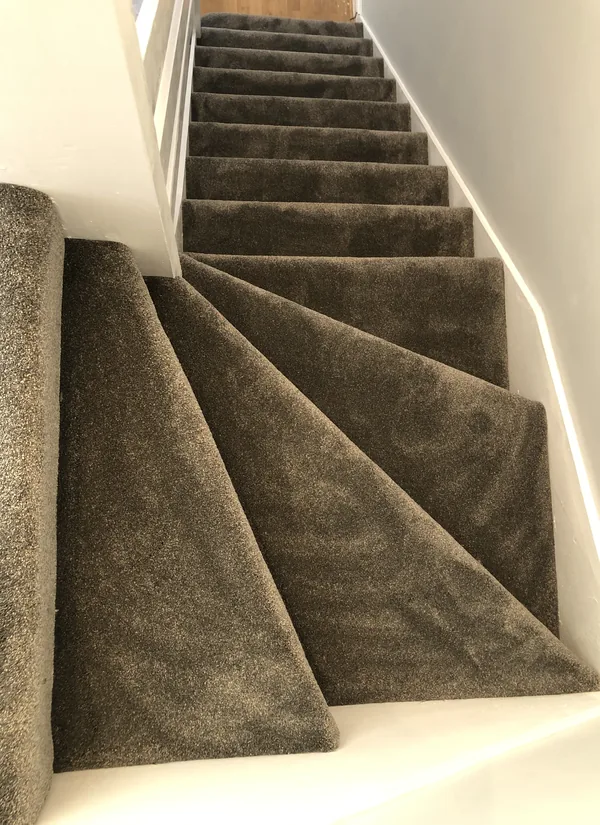Grey carpet fitted to a winder staircase, every tread cut separately